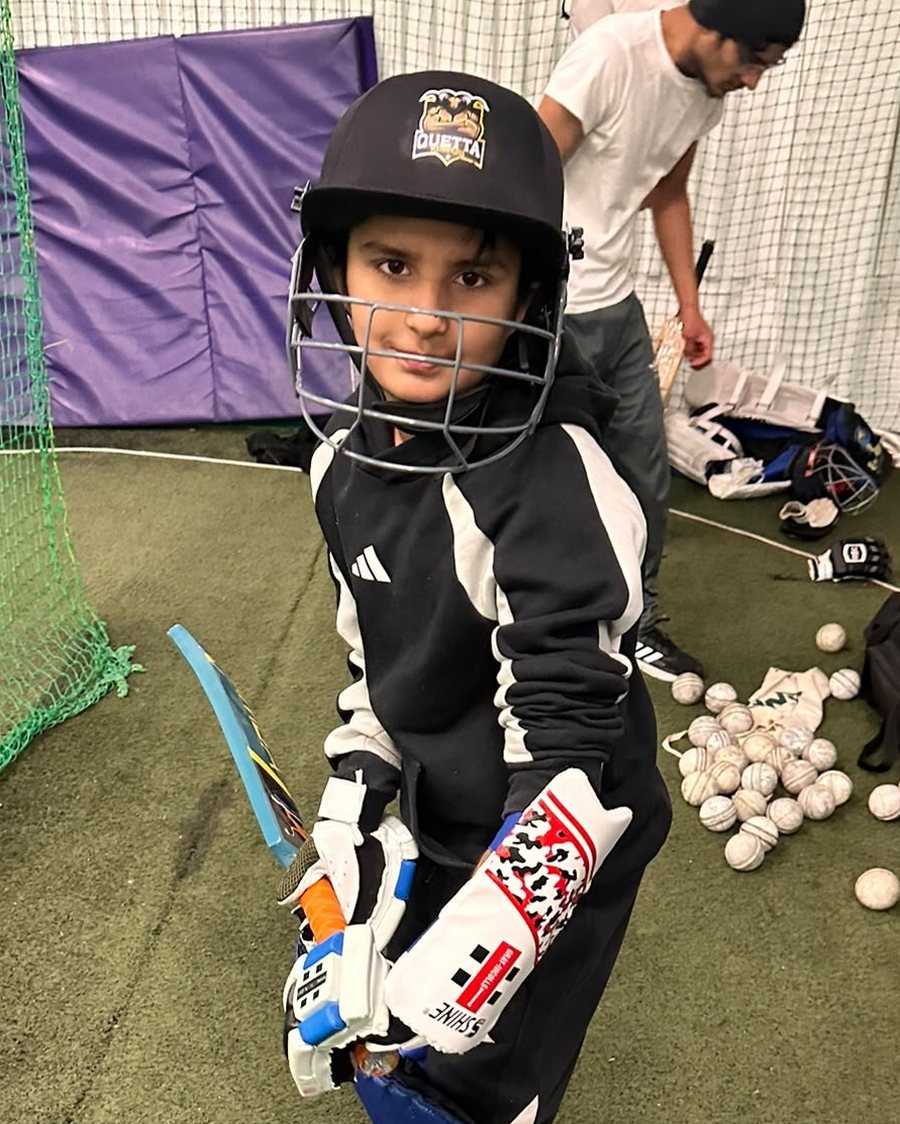 Young batter in a helmet at indoor nets training
